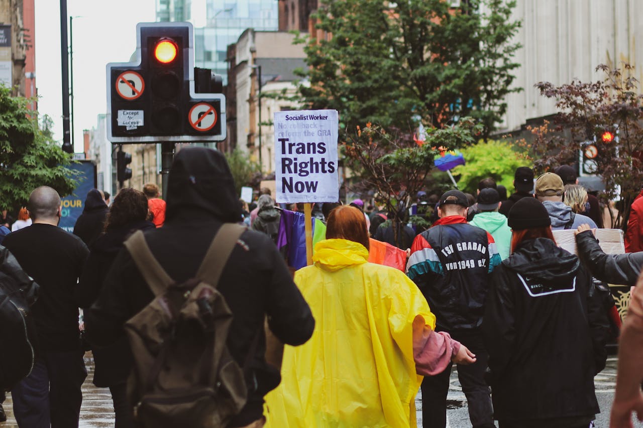 A peaceful transgender rights protest in a city street with participants holding signs and banners.