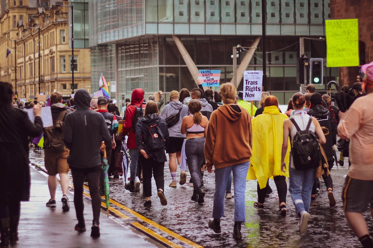 A large group peacefully protests for trans rights in a city, advocating equality.